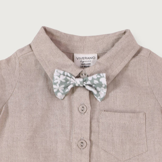 A beige linen baby romper with a detachable floral bow tie, short sleeves, a collar, and button closures.