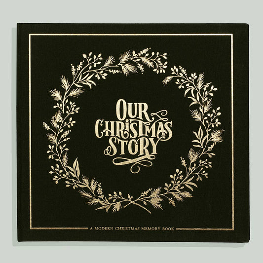 Our Christmas Story memory book, dark green linen cover with a gold foil wreath and lettering