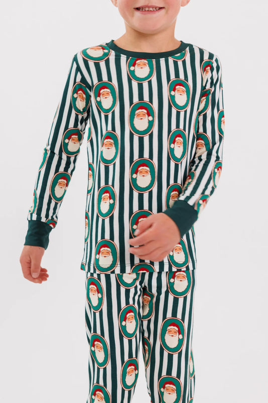 Child standing in the Green Santa Claus Lane two piece pajama set, Santa faces on green and cream stripes