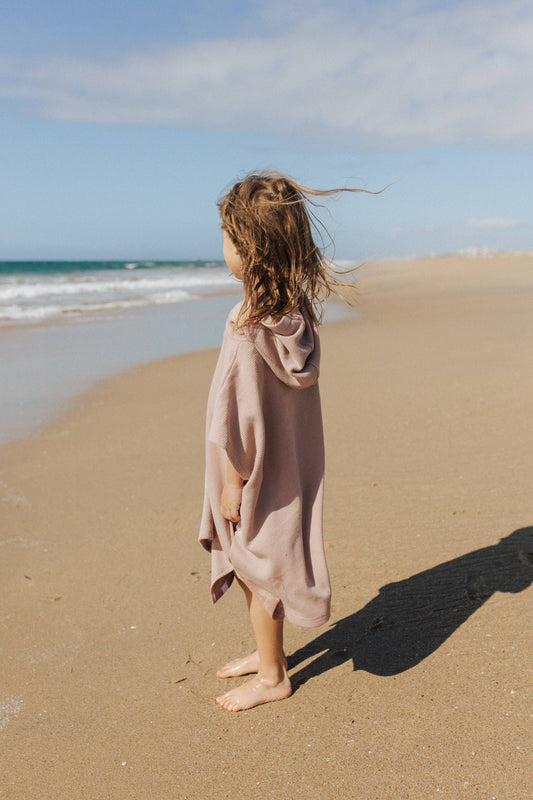 Girl on beach wearing waffle beach poncho in dusty blue