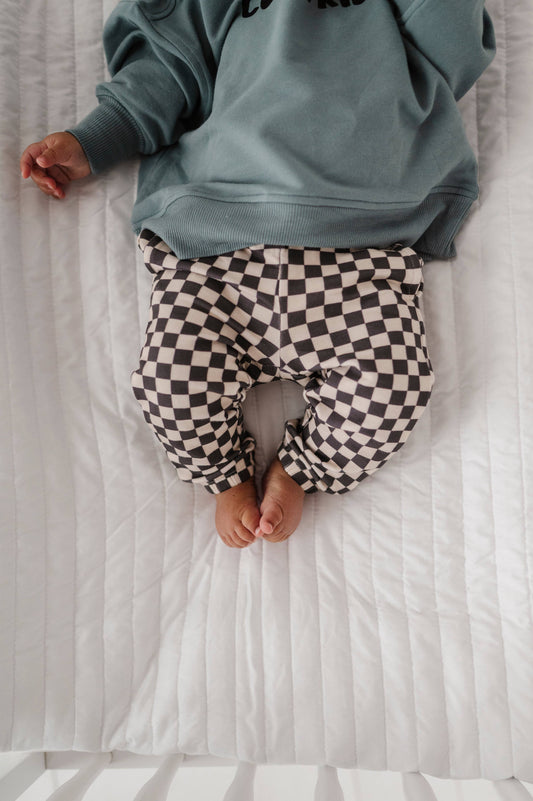 Boy laying down in crib wearing our checkered joggers and boxy cool kid sweatshirt. Our bamboo terry is made with 66% Bamboo 28% Cotton and 5% Spandex.