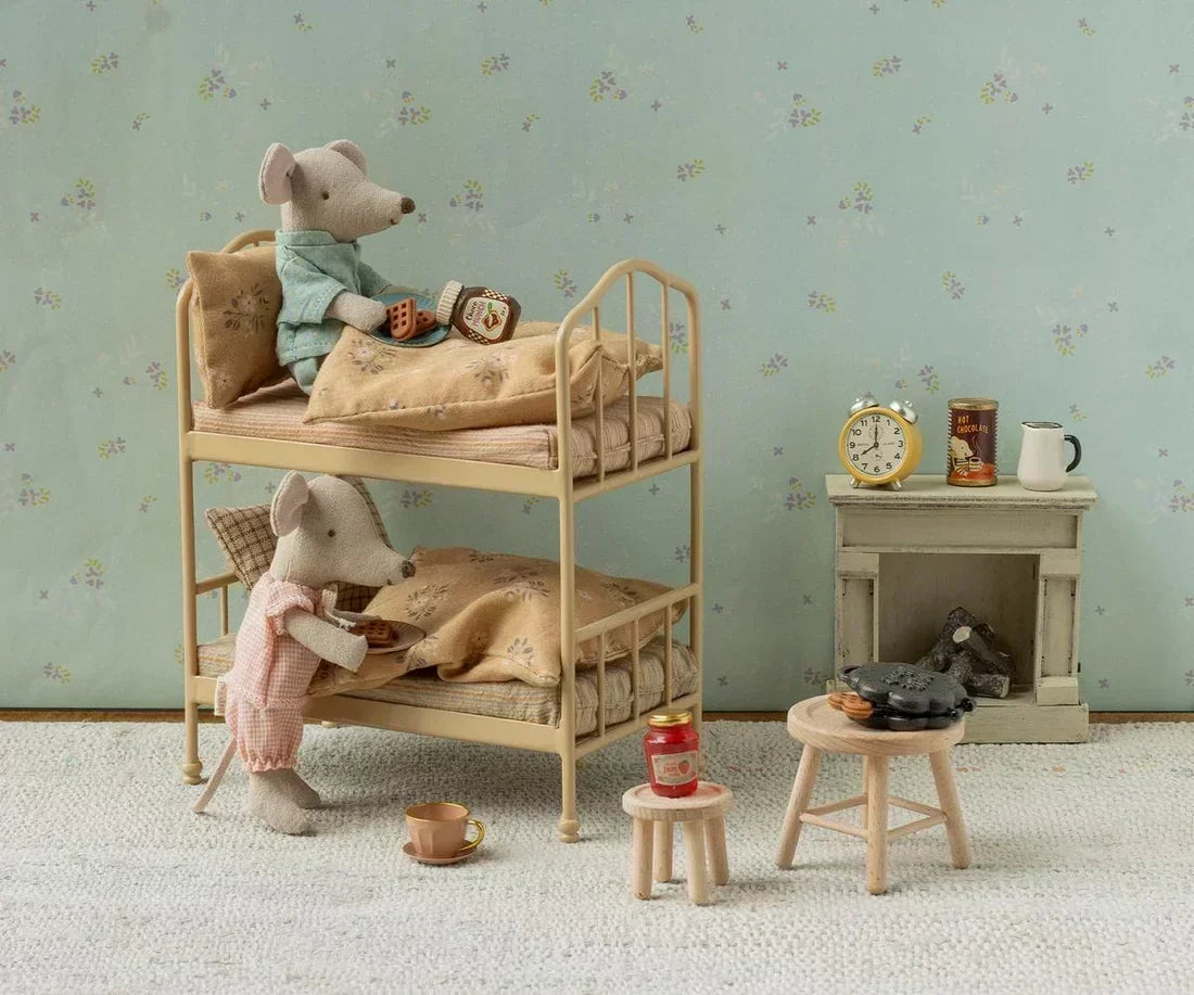 Maileg mice getting into their bunk bed with a fireplace in the background