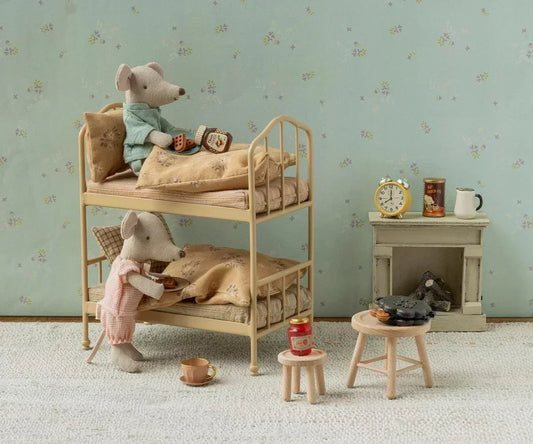 Maileg mice getting into their bunk bed with a fireplace in the background