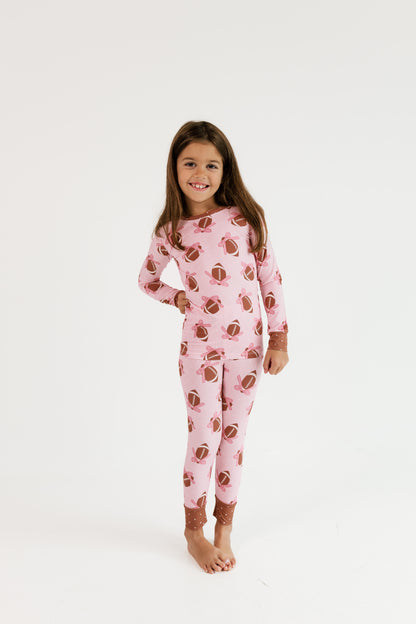 Girl wearing In My Jammers Game Day Bows two piece bamboo pajama set in pink with football bows