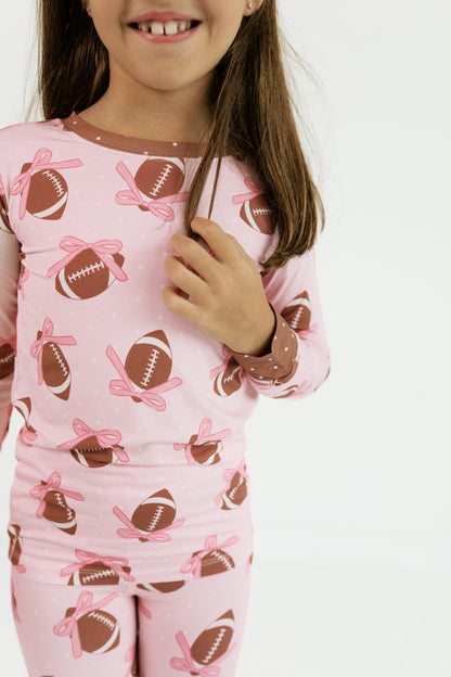 Close up of the Game Day Bows print showing pink footballs and bows on soft bamboo fabric