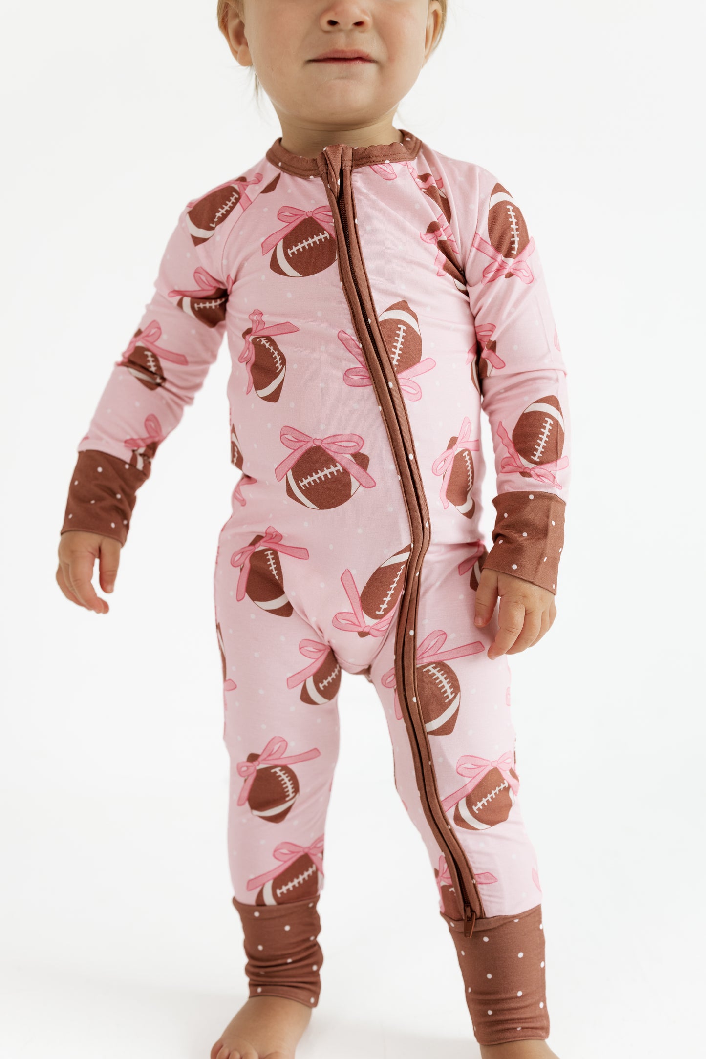 In My Jammers Game Day Bows bamboo zipper romper in pink football bow print, front view