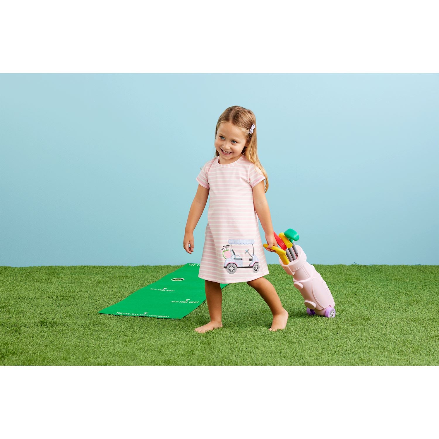 Girl showing off her 9-piece Pink golf set. Plastic golf bag holds three clubs, three balls, one hole and flag and one felt putting green. Ages 3+