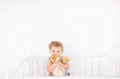 baby girl cuddling with bear snuggle blanket and fox snuggle blanket. 