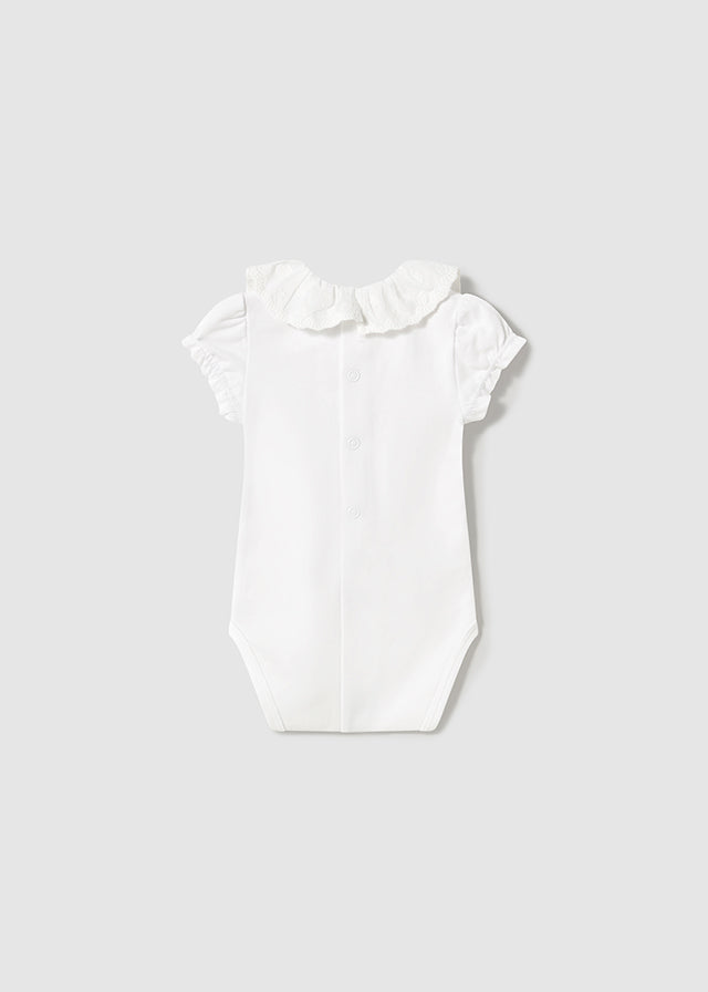 Newborn girl's white ruffled collar bodysuit.