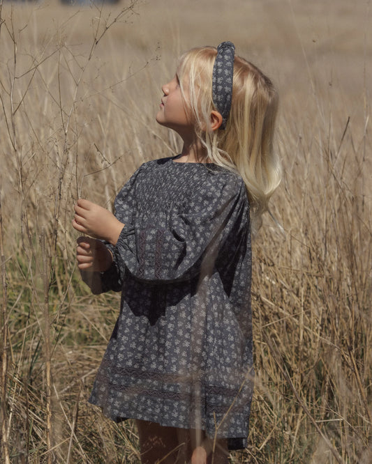 Girl in a field of tall grass wearing the Rylee + Cru Selene dress in heart ditsy print with a matching headband