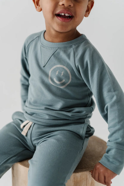 close up image of boy wearing our Smile Raglan Sweatshirt with a happy face image on left chest.