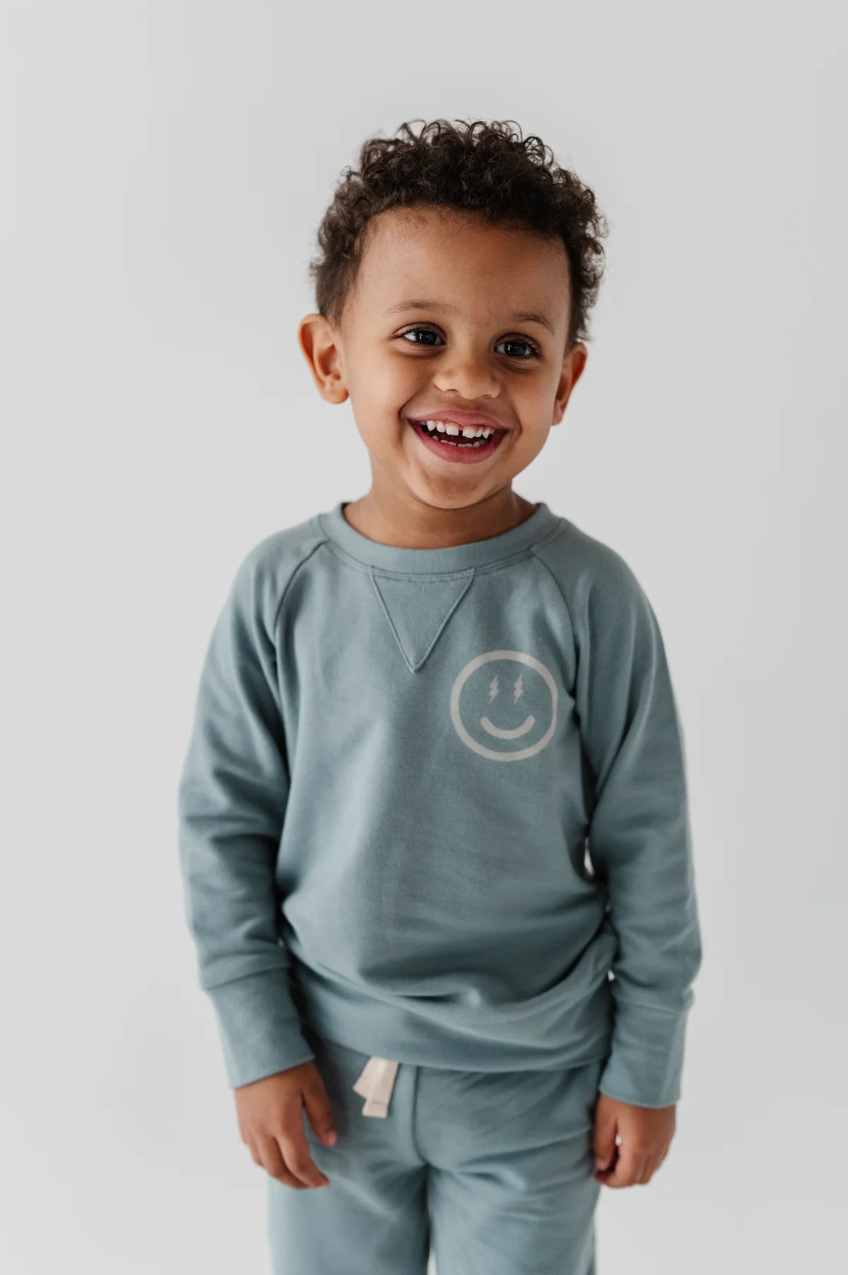 Smiling boy wearing our Smile Raglan Sweatshirt with a happy face image on left chest