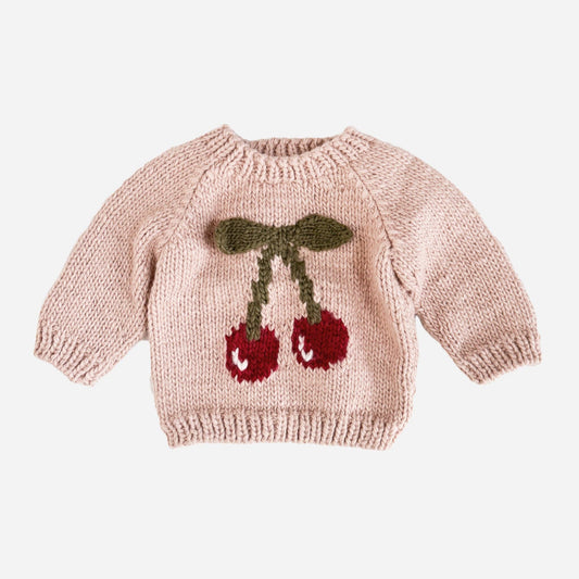 A blush-colored pullover sweater with a knitted applique of cherries and leaves on the front.