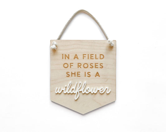 97 Design Co. Wildflower wooden banner sign reading In a field of roses she is a wildflower
