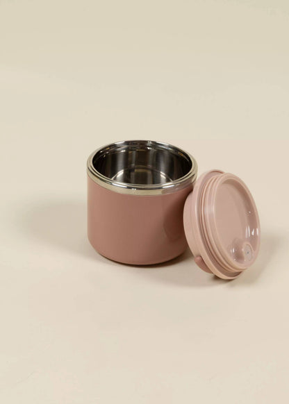 Pink food container with a silver interior and pink lid on a beige background
