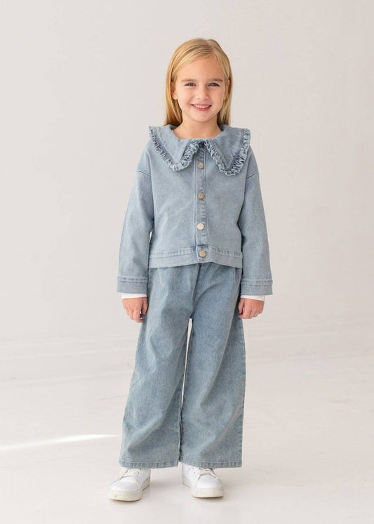 Young girl wearing a denim outfit with a ruffled collar on a light background