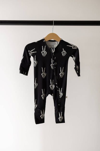 Forever French Baby Midnight Skelly bamboo zip pajamas on a hanger, black with a white skeleton hand print