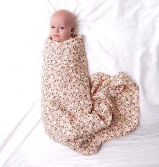 Baby swaddled in a floral blanket on a white background