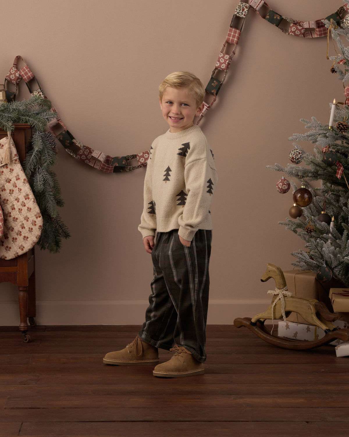 Full-length view of a boy in the Rylee + Cru Aspen tree jacquard sweater beside a Christmas tree and stockings
