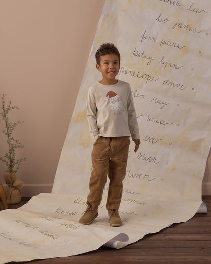 Boy standing on a handwritten backdrop wearing the Rylee + Cru Santa long sleeve tee and tan pants