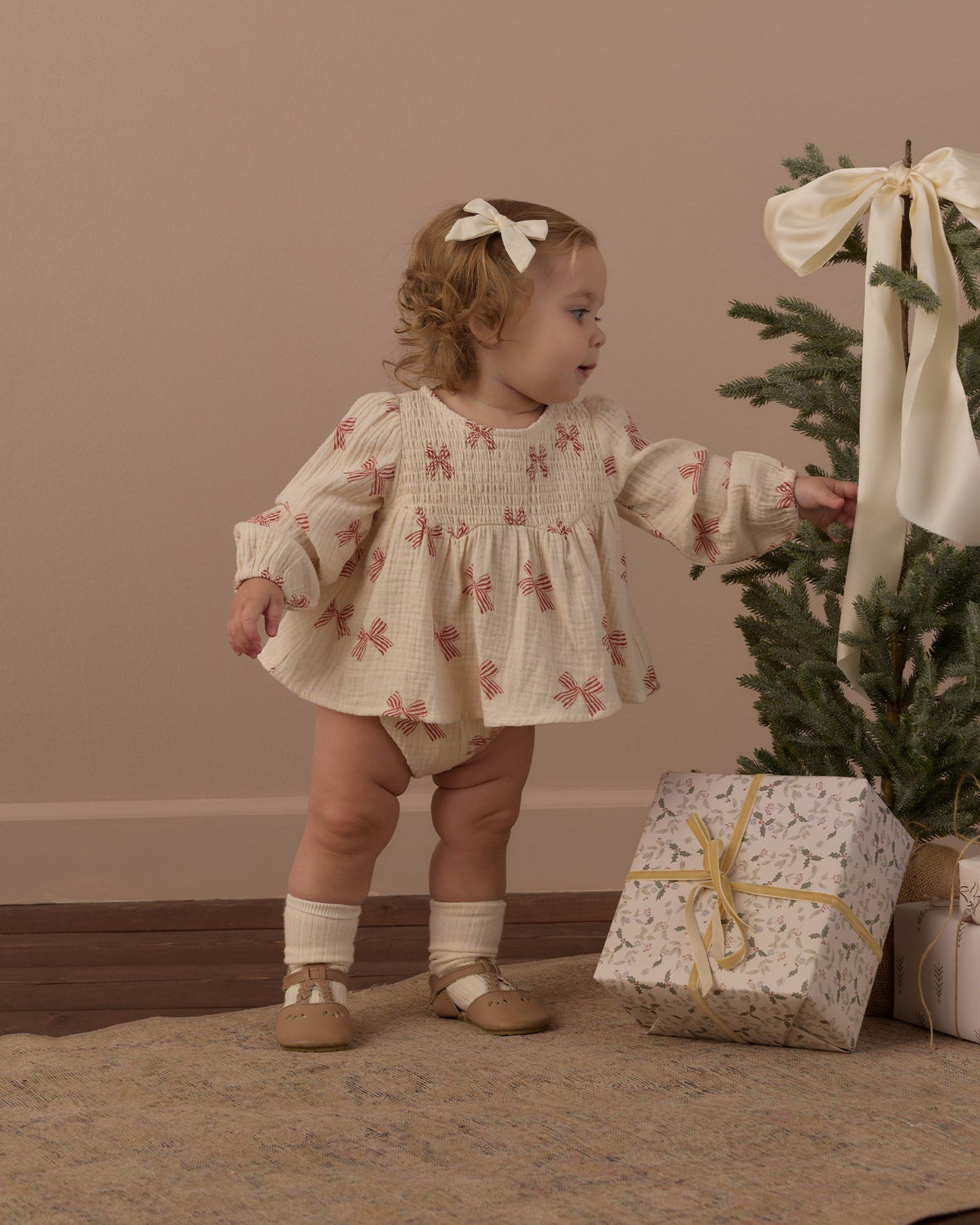 Toddler with a hair bow looking over her shoulder in the Rylee + Cru Sophia top and bloomer set in peppermint bows