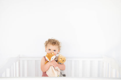 baby girl cuddling with bear snuggle blanket and fox snuggle blanket. 