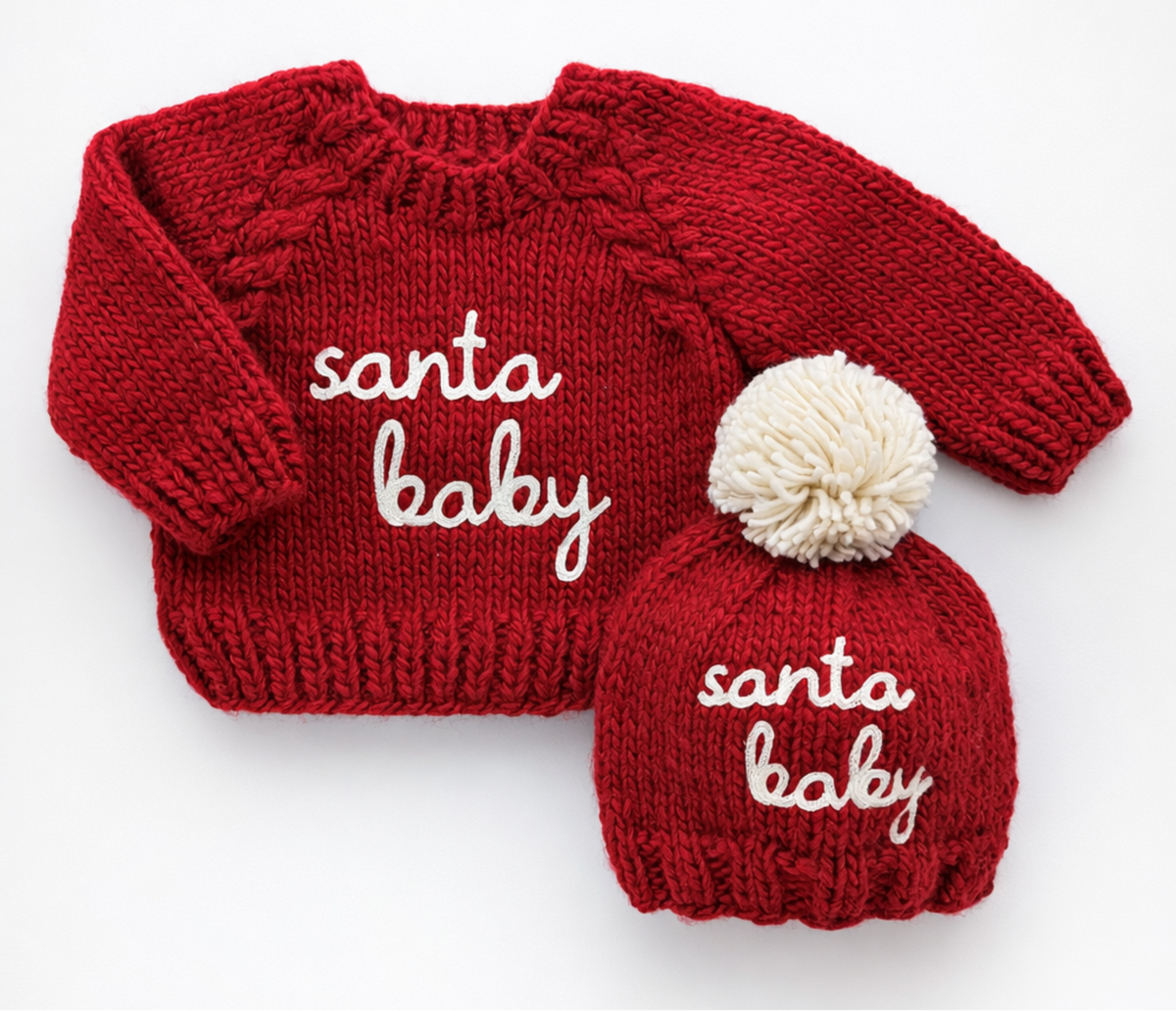Red knitted sweater and matching hat with 'Santa Baby' text on a white background