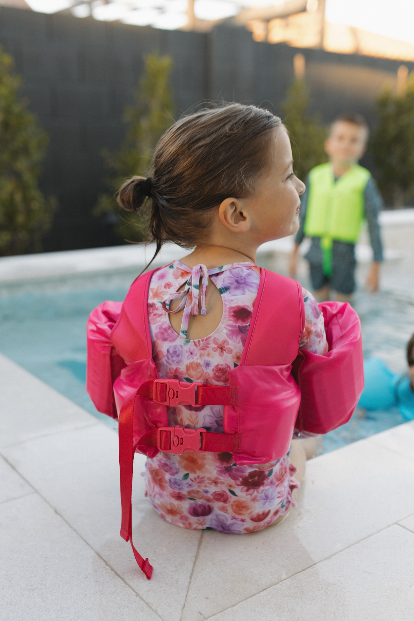 Girl sitting on the edge of a pool wearing The "Brights", Hot Pink High Visibility Neon Swim Floaties