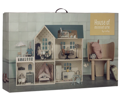 The packaging box for 'House of miniature by Maileg', featuring a detailed illustration of a miniature dollhouse with a wooden chair and a pink plush toy, set against a light green tiled background.