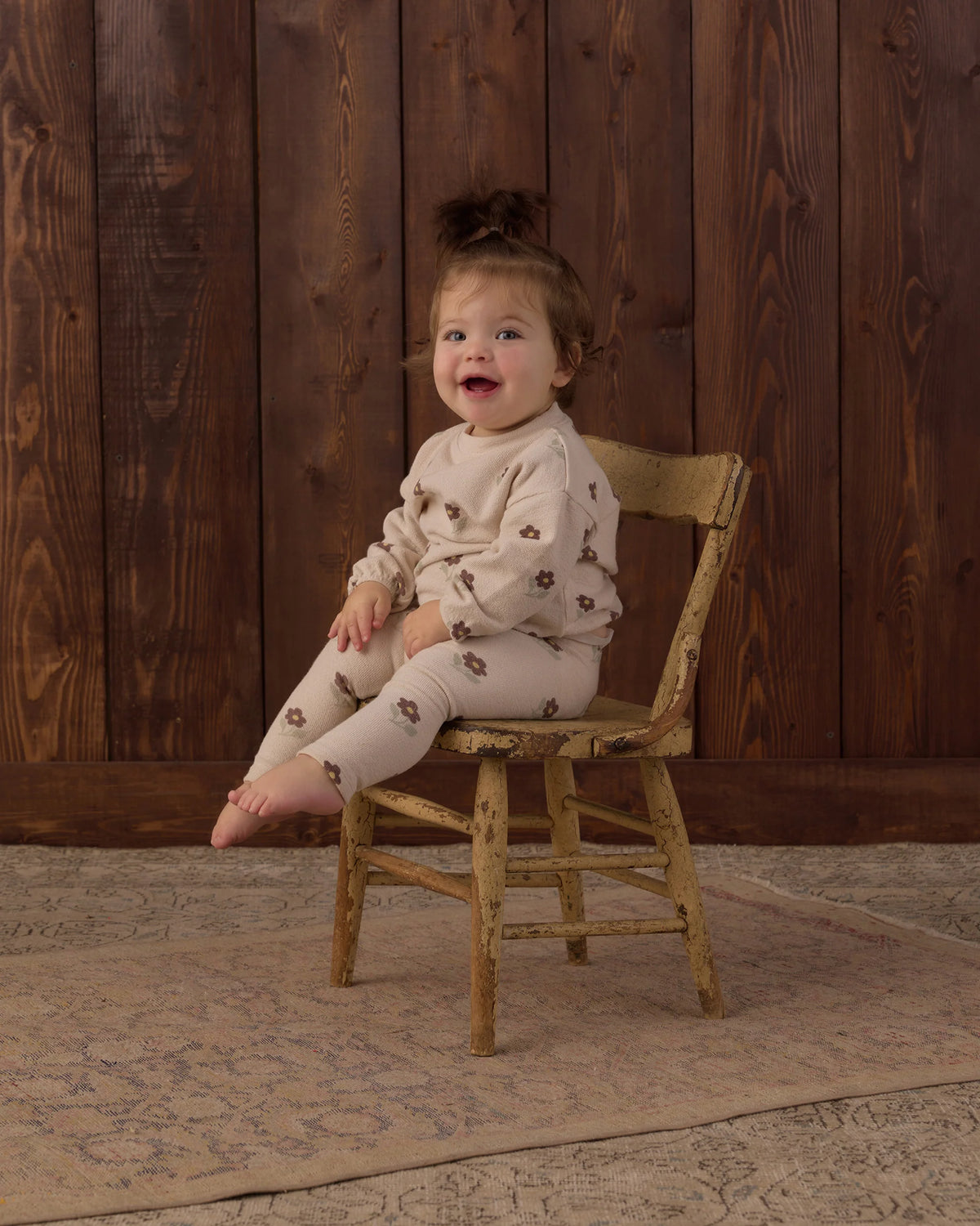 Toddler girl laughing on a wooden chair in the Rylee + Cru Spongey Knit Set in Petal Daisy