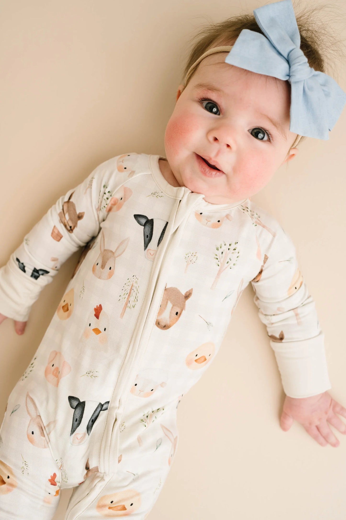 Baby wearing Farm Friends bamboo sleeper with watercolor farm animal print including horses, pigs, bunnies, chicks, and lambs