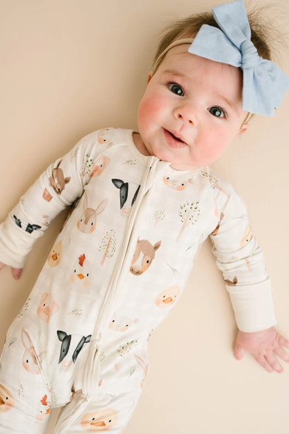 Baby wearing Farm Friends bamboo sleeper with watercolor farm animal print including horses, pigs, bunnies, chicks, and lambs