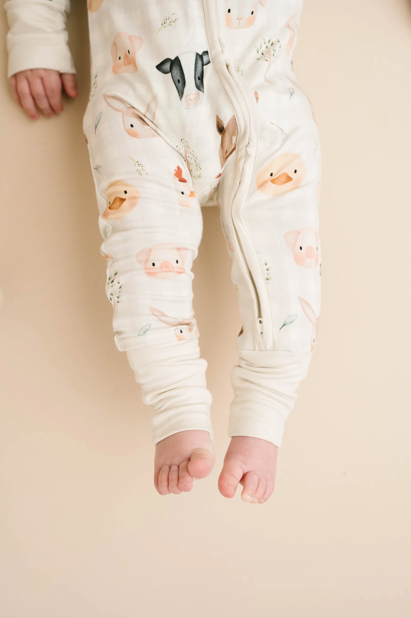 Baby wearing Farm Friends bamboo sleeper with watercolor farm animal print including horses, pigs, bunnies, chicks, and lambs