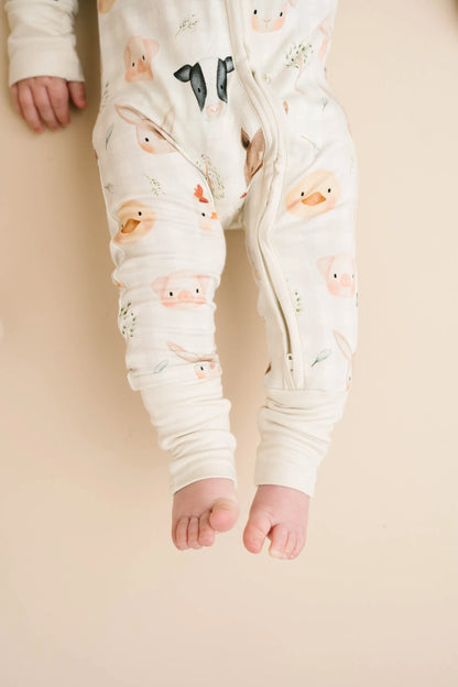 Baby wearing Farm Friends bamboo sleeper with watercolor farm animal print including horses, pigs, bunnies, chicks, and lambs