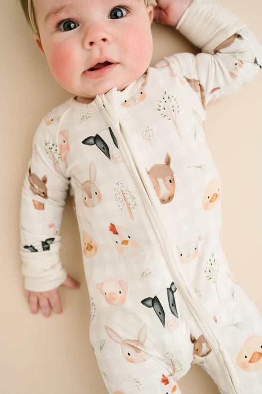 Baby wearing Farm Friends bamboo sleeper with watercolor farm animal print including horses, pigs, bunnies, chicks, and lambs