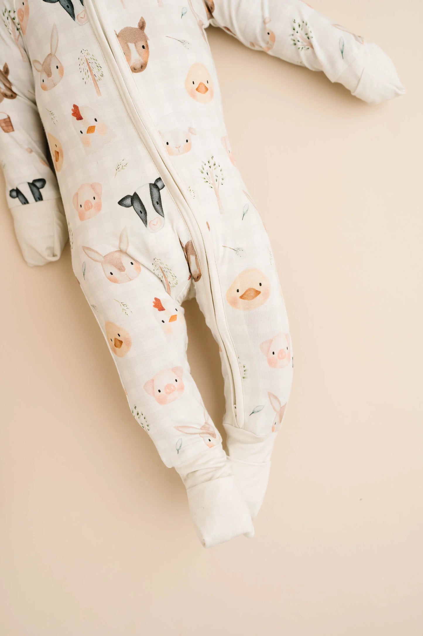 Baby wearing Farm Friends bamboo sleeper with watercolor farm animal print including horses, pigs, bunnies, chicks, and lambs