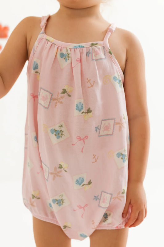 Child wearing a pink bubble romper with floral patterns on a white background