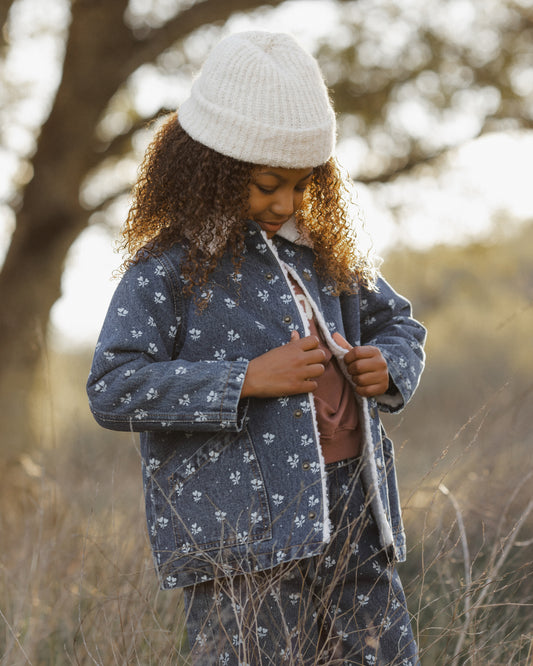 Child outdoors in a grassy field wearing the Rylee + Cru Long Chore Coat in Heart Ditsy blue floral print with a white knit beanie