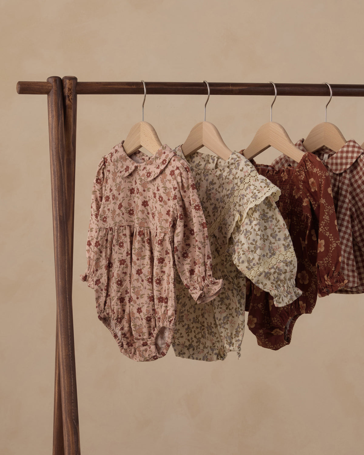 Rylee + Cru Cora romper in pink floral hanging on a clothing rack