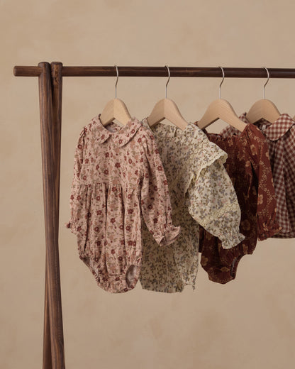 Rylee + Cru Cora romper in pink floral hanging on a clothing rack