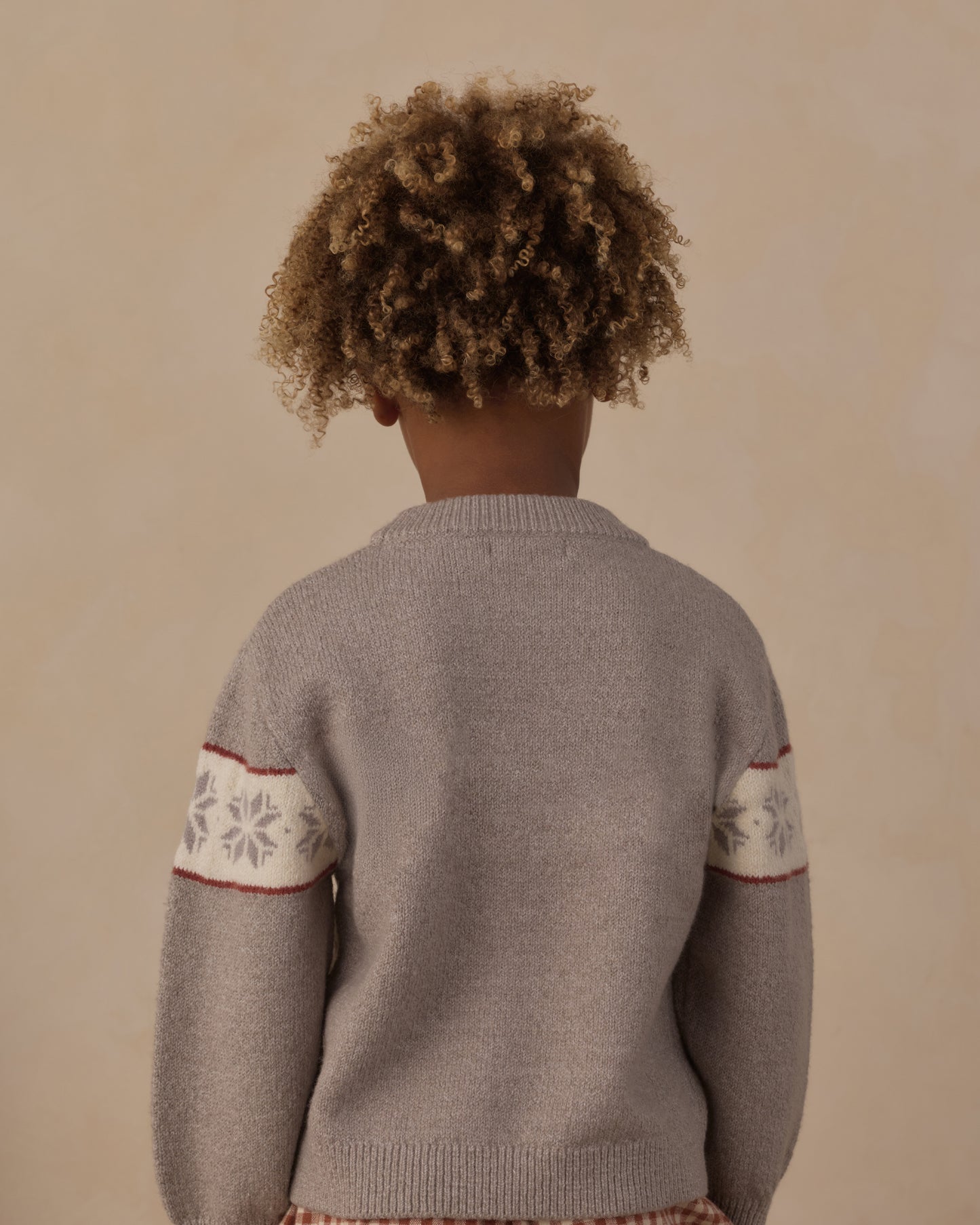 Back of the Rylee + Cru Reagan Apres Ski sweater worn by a child, showing the snowflake bands on the sleeves