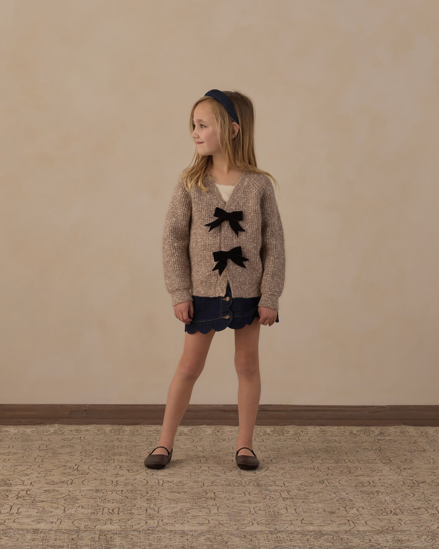 Girl standing in the Rylee + Cru Bow Cardigan in heathered stone with navy shorts