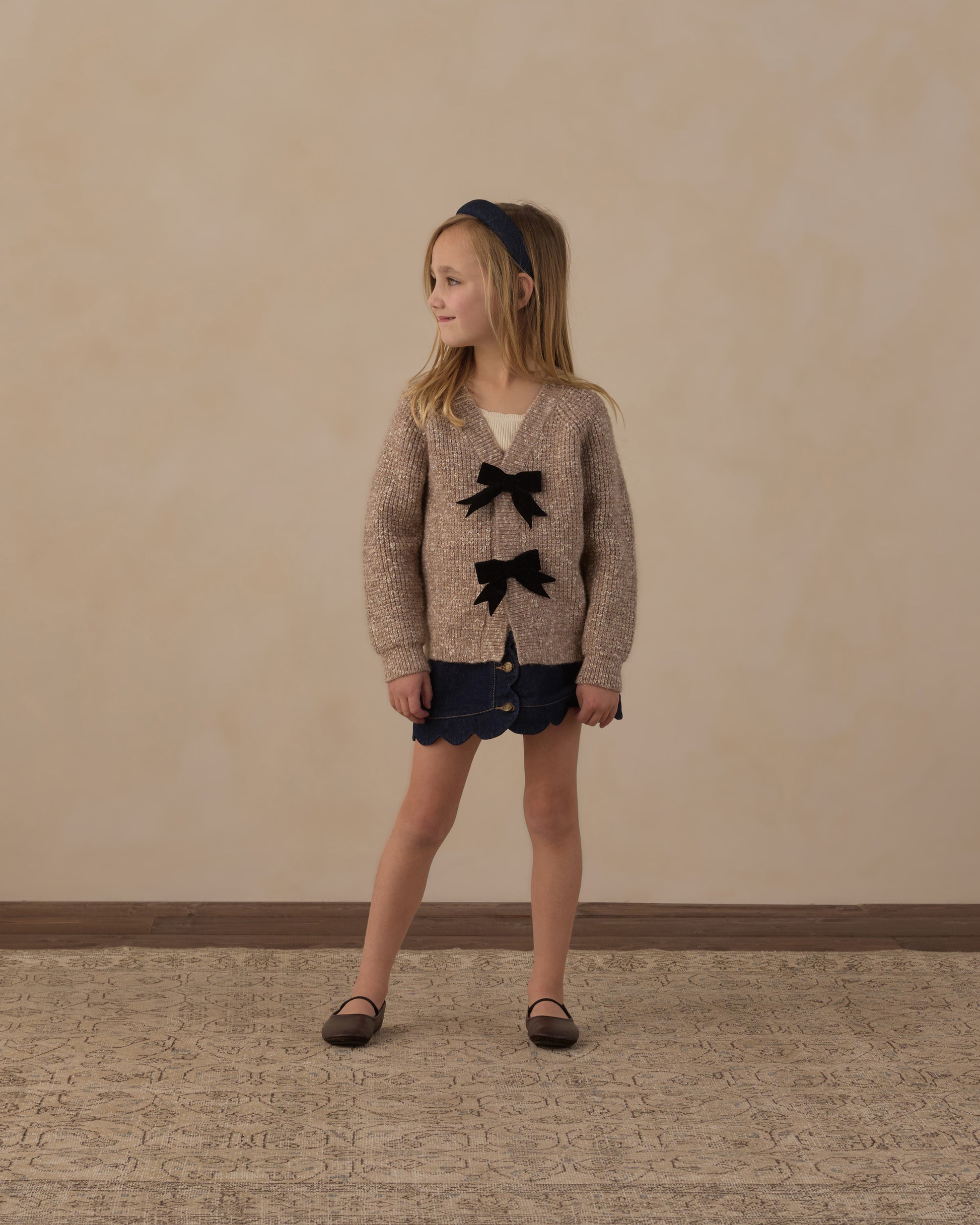 Girl standing in the Rylee + Cru Bow Cardigan in heathered stone with navy shorts