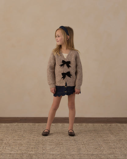 Girl standing in the Rylee + Cru Bow Cardigan in heathered stone with navy shorts