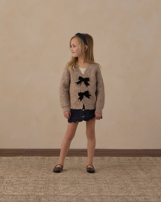 Girl standing in the Rylee + Cru Bow Cardigan in heathered stone with navy shorts