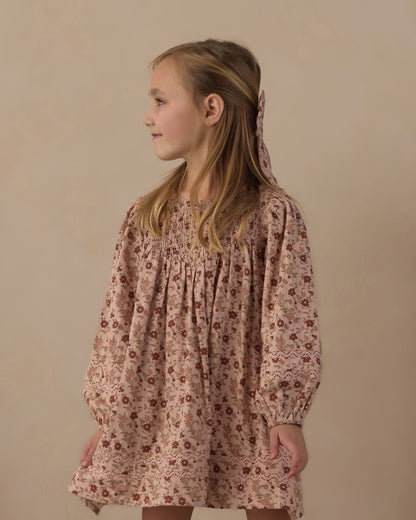 Girl wearing the Rylee + Cru Selene dress in pink floral, close view of the smocked bodice and long sleeves
