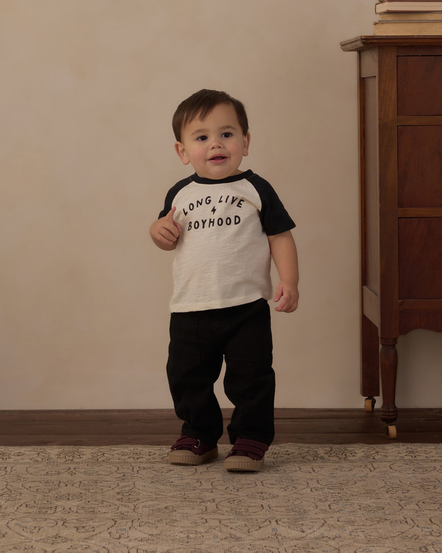 Toddler standing in the Long Live Boyhood raglan tee with black pants