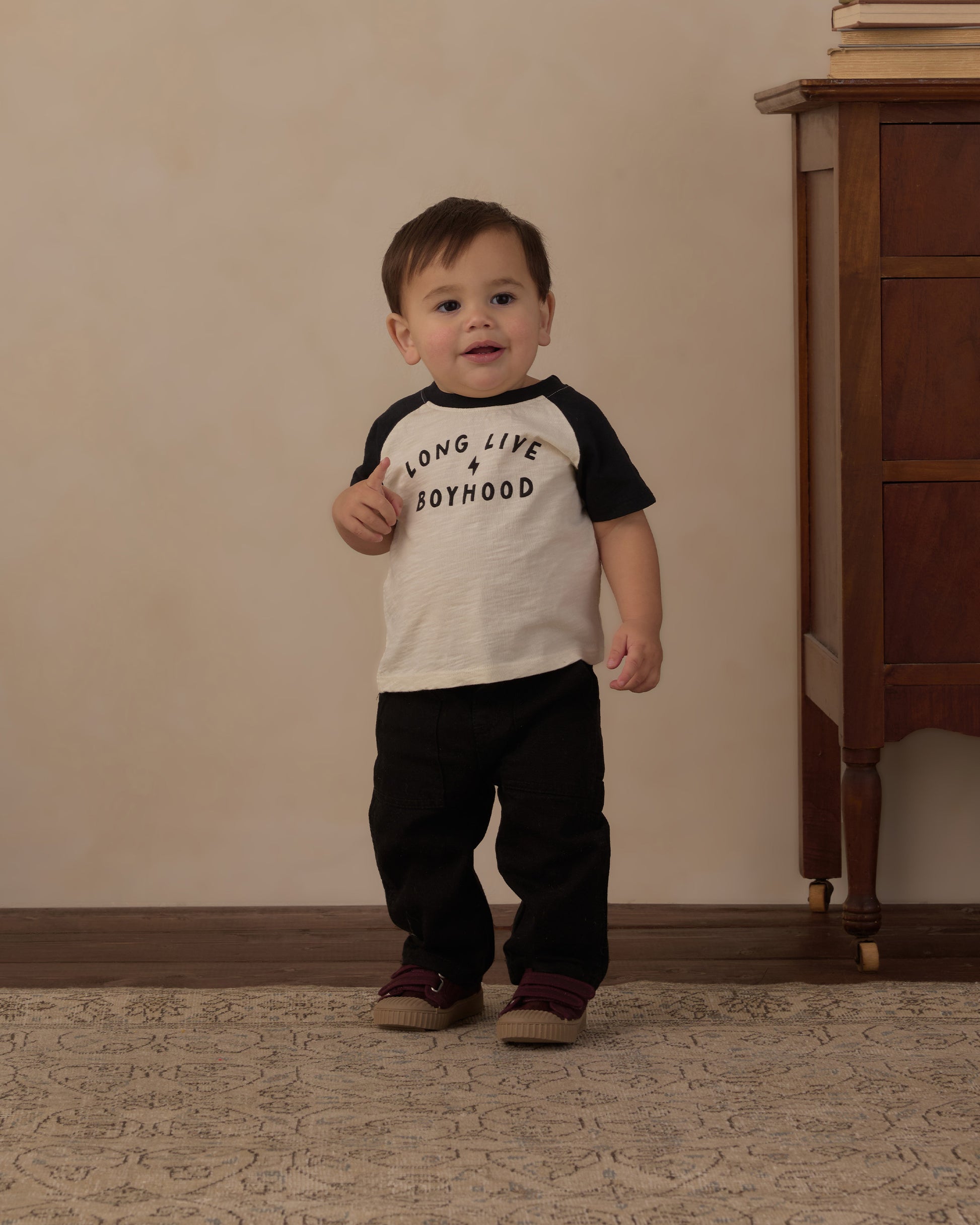 Toddler standing in the Long Live Boyhood raglan tee with black pants
