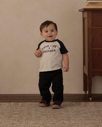 Toddler standing in the Long Live Boyhood raglan tee with black pants
