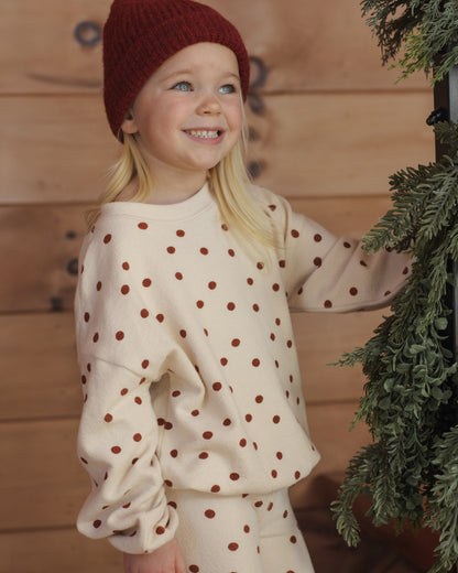 Girl smiling up at holiday greenery in the Rylee + Cru ruby dots spongey knit top